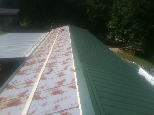 Old rusted panels beside newly installed green metal roofing — Wind Damage Roof Repair by Roofing Brothers in Kimbolton