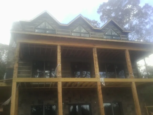 Dormers and porch framing on a large log home under construction — Roof Coating work by our crew in Kimbolton
