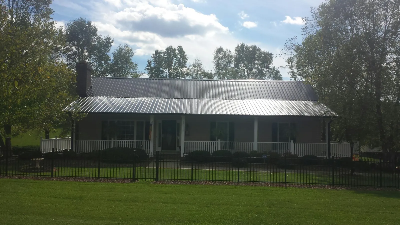 Gray metal roof on a brick ranch with a full width front porch — Gutter Guard Installation work by our crew in Kimbolton