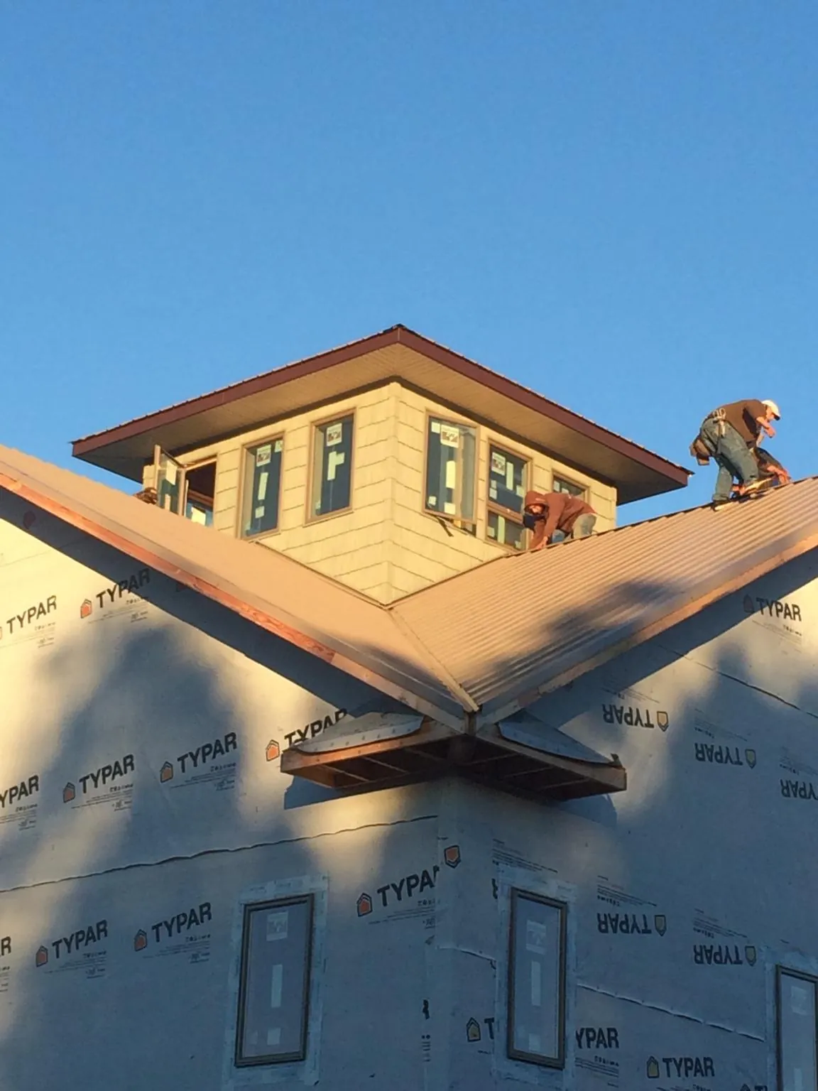 Roofers working around a rooftop cupola on a new metal roof at sunset — Roof Waterproofing in Kimbolton by Roofing Brothers